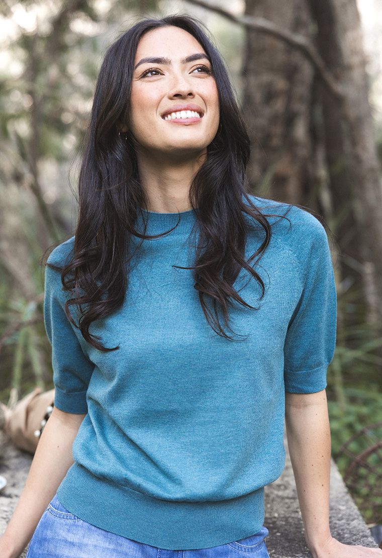 Model in lifestyle setting wearing Aurora Top in Turquoise, close-up front view with nature background 
