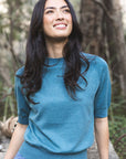 Model in lifestyle setting wearing Aurora Top in Turquoise, close-up front view with nature background 