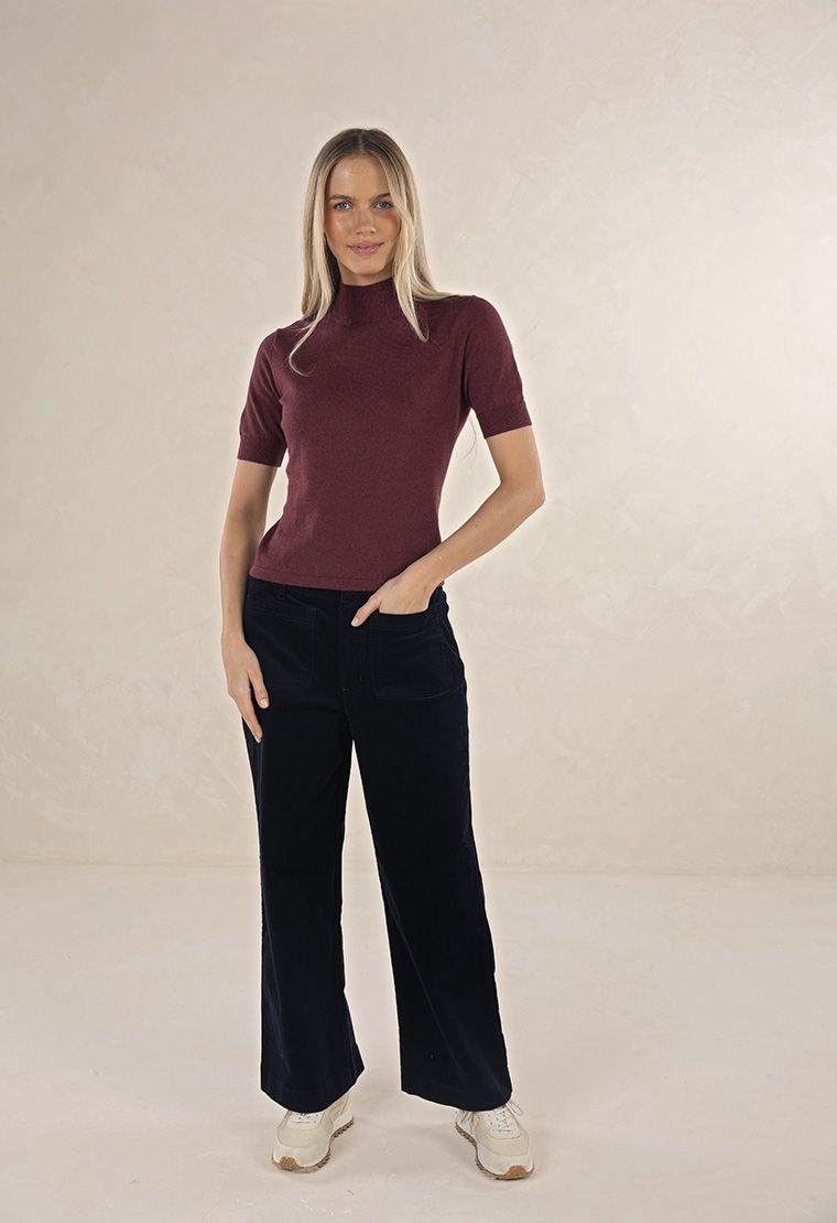 Model in studio wearing Suki Cord Pant in Indigo and Vera Top in Claret with cream sneakers, full-length front view 