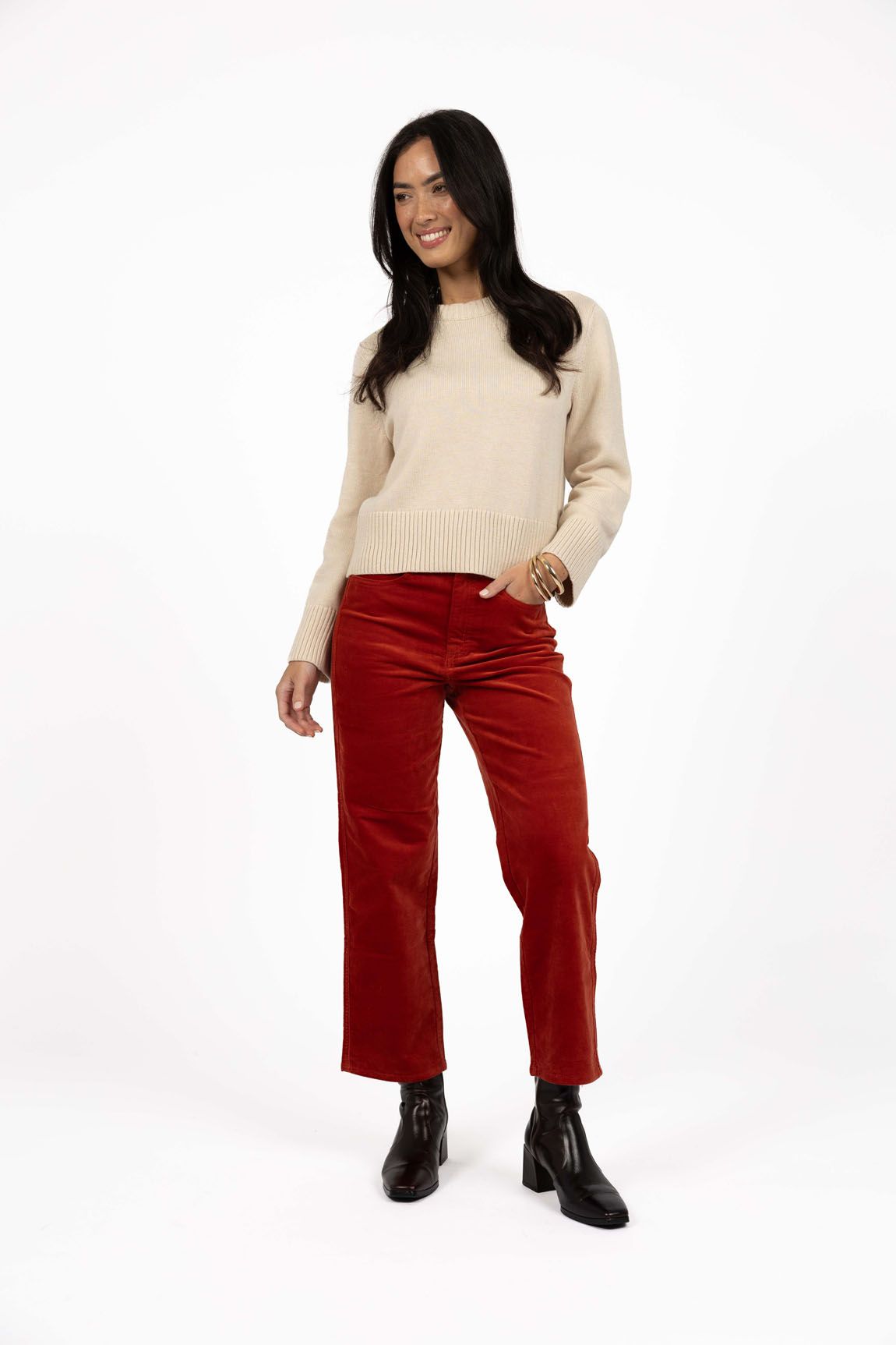 Model in studio wearing Va Va Velour Pant in Rust with Rexie Jumper in Cream and black boots, full-length front view 