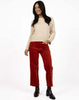 Model in studio wearing Va Va Velour Pant in Rust with Rexie Jumper in Cream and black boots, full-length front view 