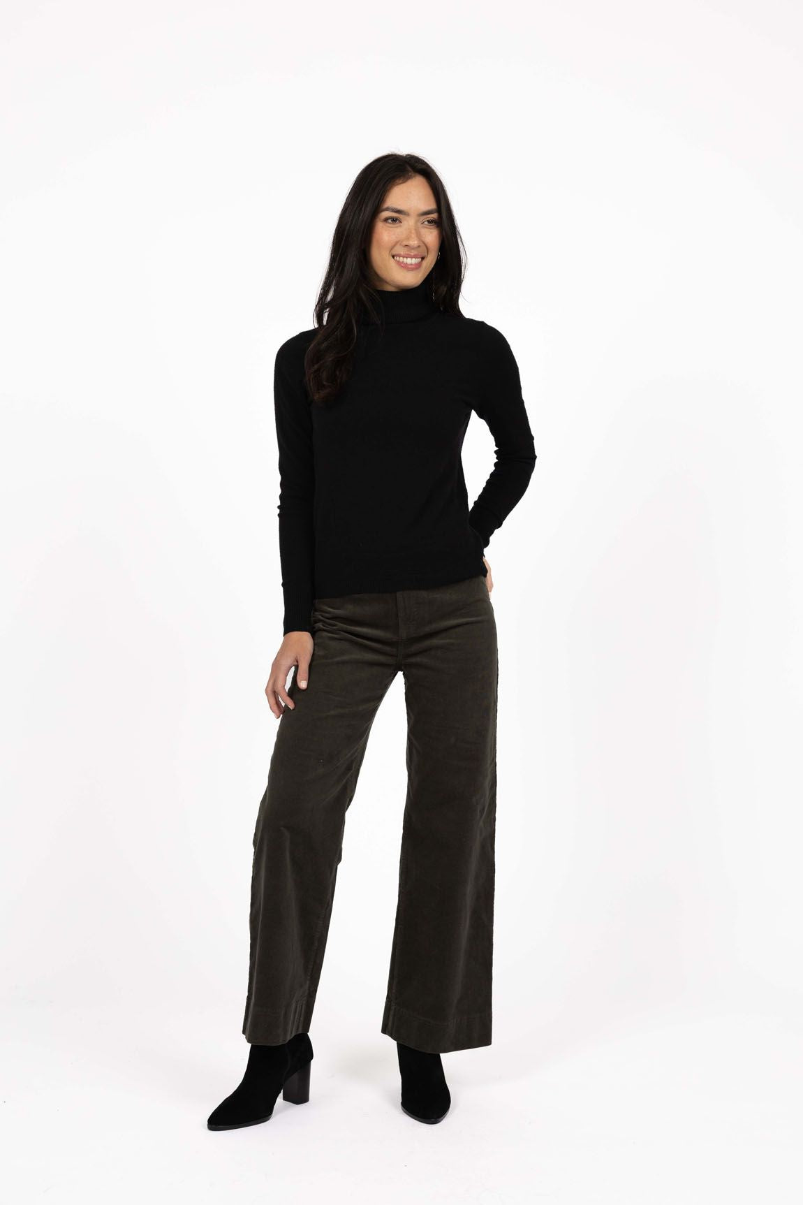 Model in studio wearing Alana Skivvy in Black with Va Va Velour Pant in Khaki and black boots, full-length front view 