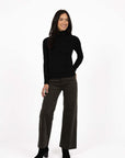 Model in studio wearing Alana Skivvy in Black with Va Va Velour Pant in Khaki and black boots, full-length front view 