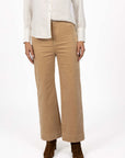 Model in studio wearing Fleetwood Cord Pant in Wheat with Pixie Shirt in White and brown boots, close-up front view showing wide leg 