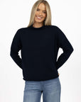 Model in studio wearing Divine Jumper in Navy with Ryder Jean, close-up front view  