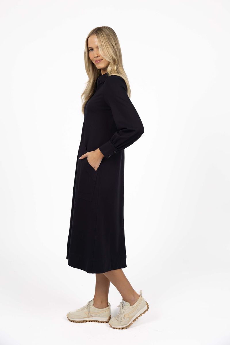 Model in studio wearing Dune Midi Dress in Navy with white sneakers, full-length side view  