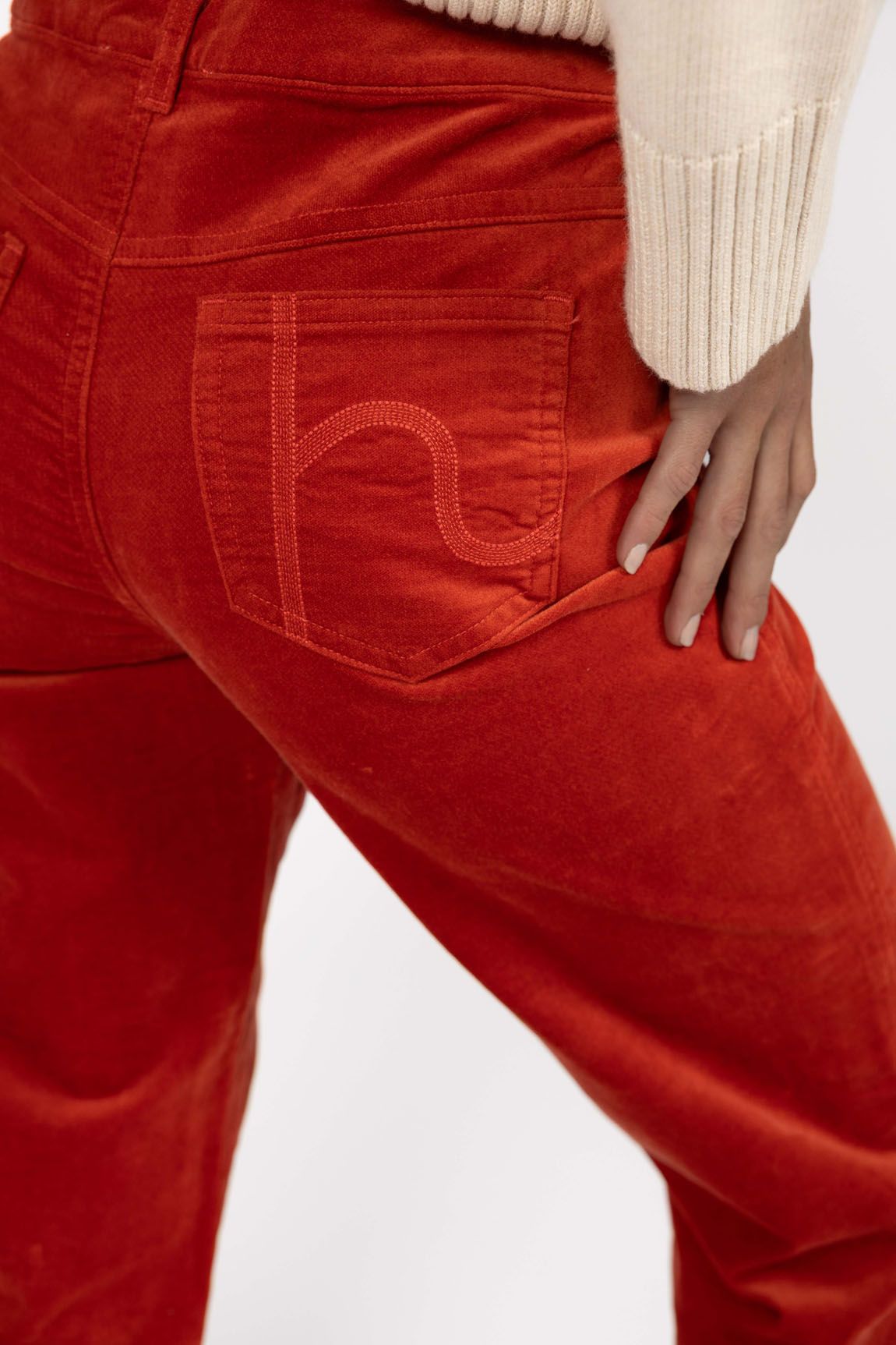 Model in studio wearing Va Va Velour Pant in Rust, close-up back view showing pocket embroidery  