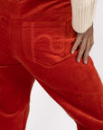 Model in studio wearing Va Va Velour Pant in Rust, close-up back view showing pocket embroidery  