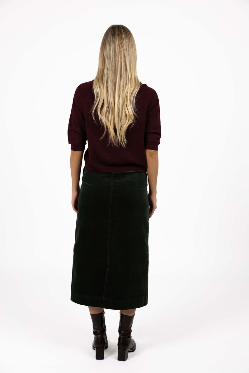 Model in studio wearing Grace Top in Merlot with Va Va Velour Skirt in Pine, full-length back view  
