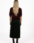 Model in studio wearing Grace Top in Merlot with Va Va Velour Skirt in Pine, full-length back view  