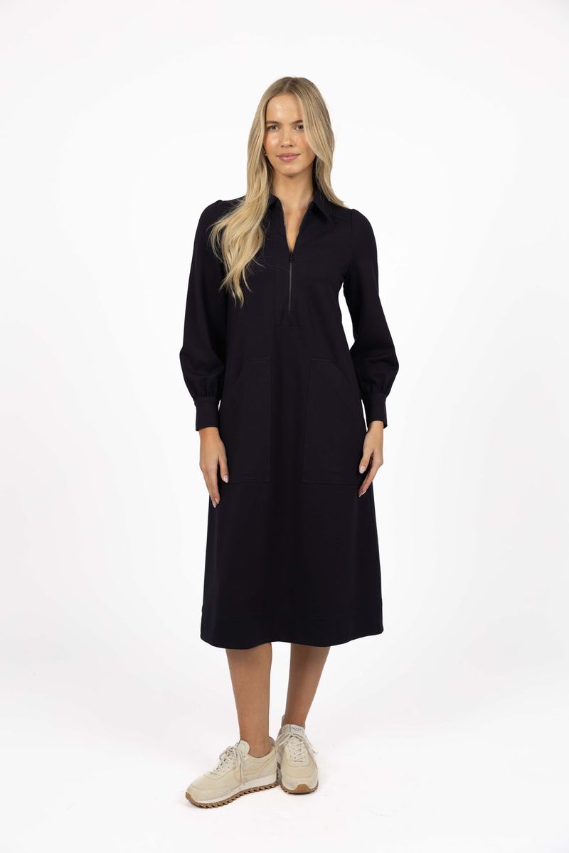 Model in studio wearing Dune Midi Dress in Navy with white sneakers, full-length front view showing midi length  