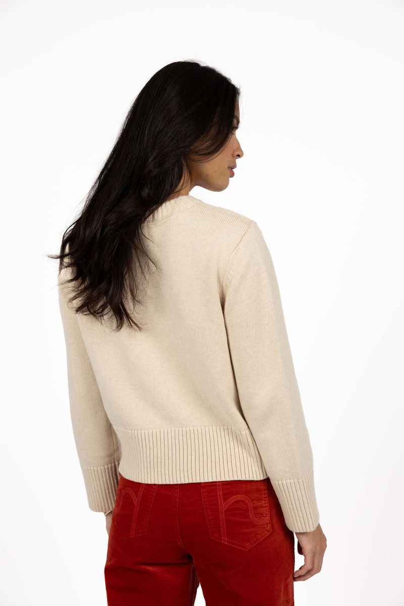 Model in studio wearing Rexie Jumper in Cream with Va Va Velour Pant in Rust, close-up back view 