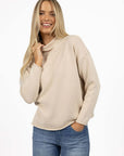 Model in studio wearing Divine Jumper in Stone with Ryder Jean, close-up front view holding collar  