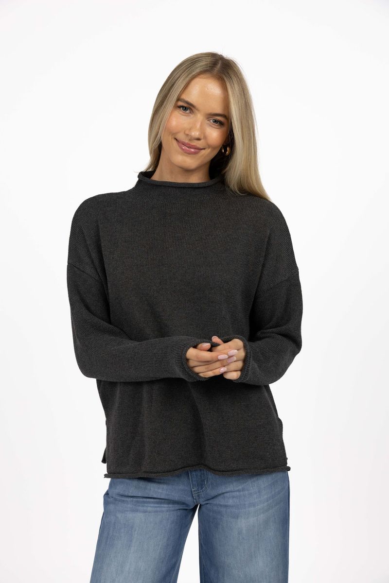 Model in studio wearing Divine Jumper in Charcoal with Ryder Jean, close-up front view showing rolled cuffs, hem and collar 