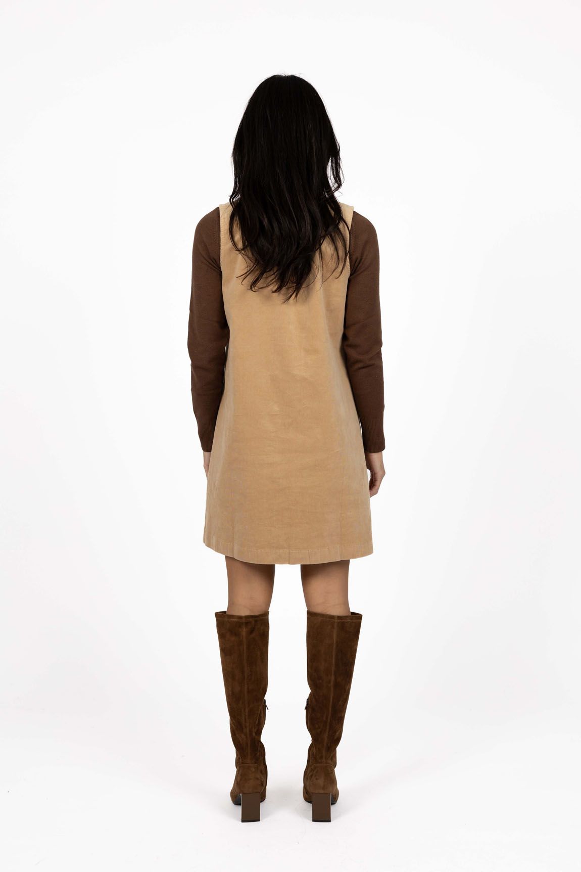 Model in studio wearing Nova Cord Dress in Wheat over the Alana Skivvy in Chocolate with brown boots, full-length back view 