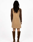 Model in studio wearing Nova Cord Dress in Wheat over the Alana Skivvy in Chocolate with brown boots, full-length back view 