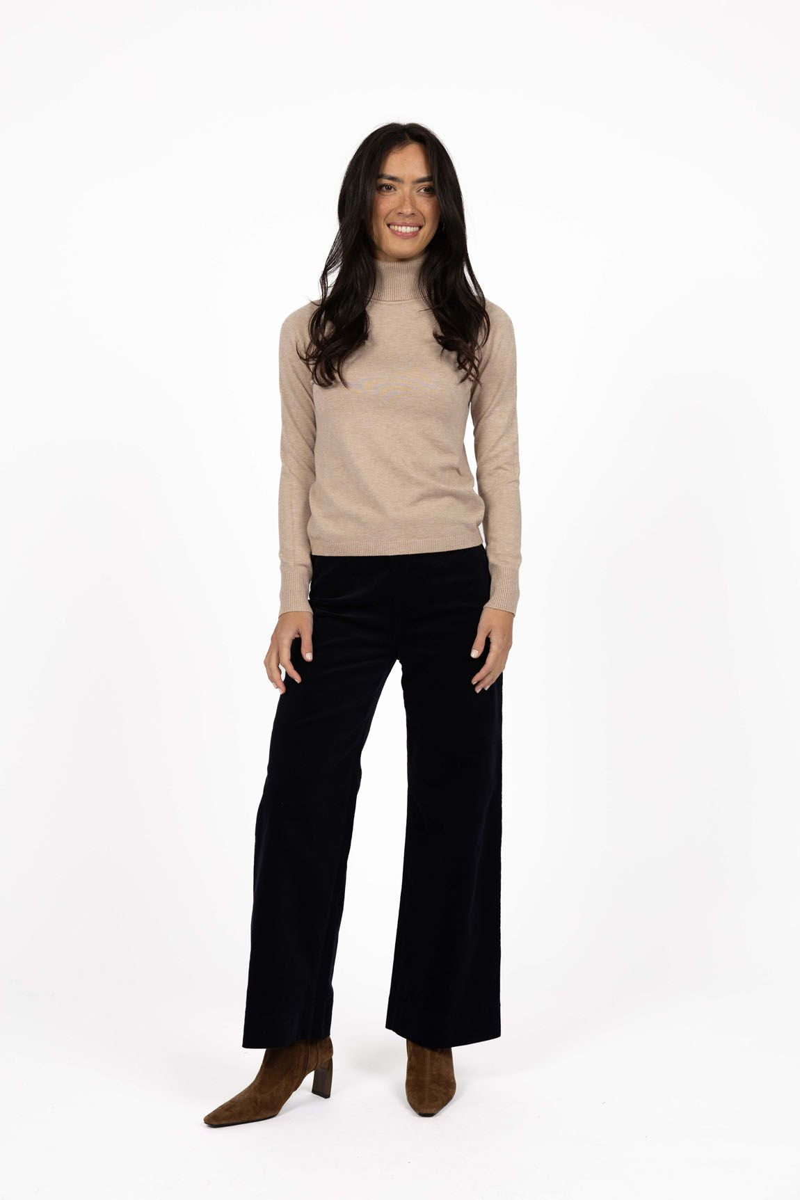 Model in studio wearing Alana Skivvy in Birch with Va Va Velour Pant in Black and brown boots, full-length front view  