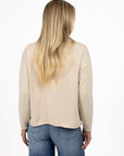Model in studio wearing Divine Jumper in Stone with Ryder Jean, close-up back view  