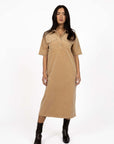Model in studio wearing Amici Cord Dress in Wheat with brown boots, full-length front view  