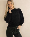 Model in studio wearing Chenille Jumper in Black with Va Va Velour Pant in Pine, close-up front view 