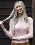 Model in lifestyle setting wearing Tempo Top in Shell Pink with Stitched Luxe Pant in Camel, close-up front view  