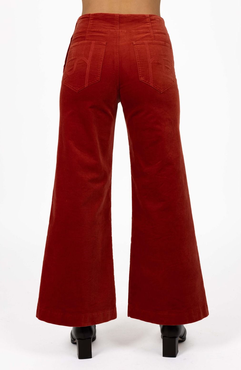 Model in studio wearing Stitched Luxe Pant in Rust with black boots, close-up back view showing pocket embroidery  
