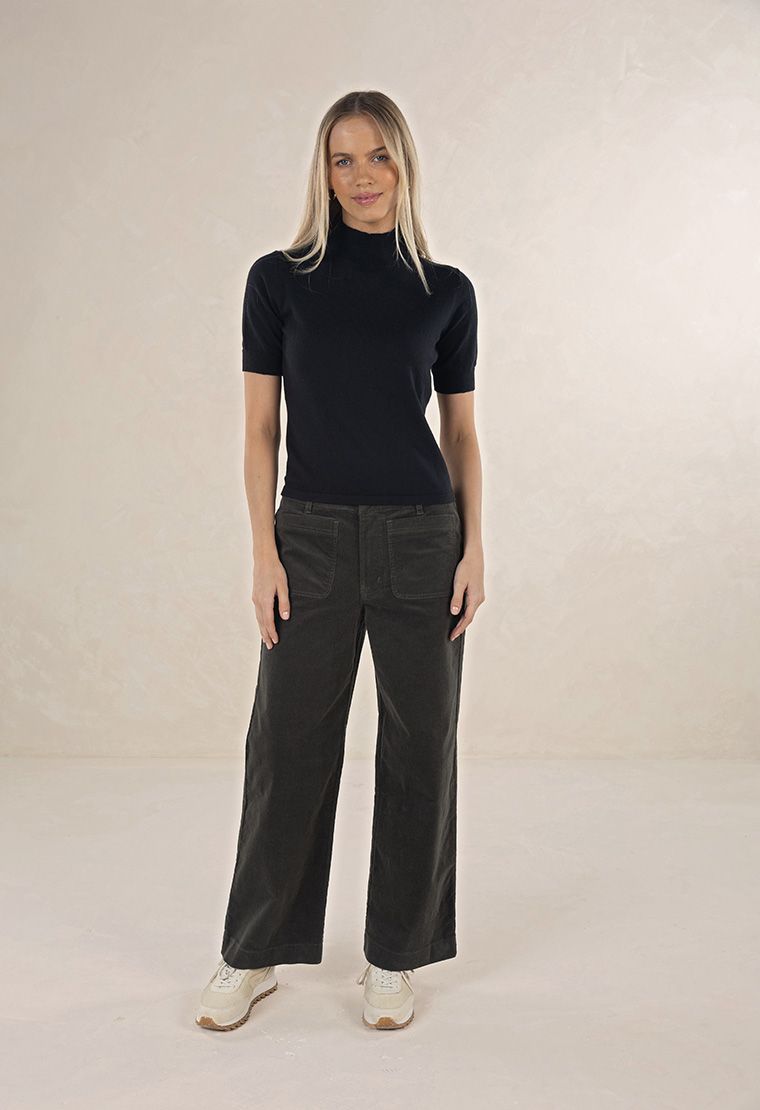 Model in studio wearing Suki Cord Pant in Khaki and Vera Top in Black with cream sneakers, full-length front view 