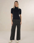 Model in studio wearing Suki Cord Pant in Khaki and Vera Top in Black with cream sneakers, full-length front view 