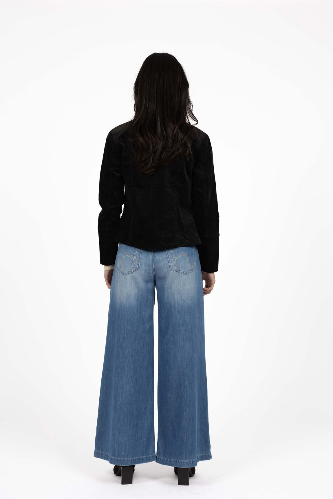 Model in studio wearing Gabi Jacket in Black with Ryder Jean and black boots, full-length back view 