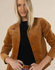 Model in studio wearing Gabi Jacket in Camel over black tee and Ryder Jean with tan Classic Belt, close-up front view holding belt  