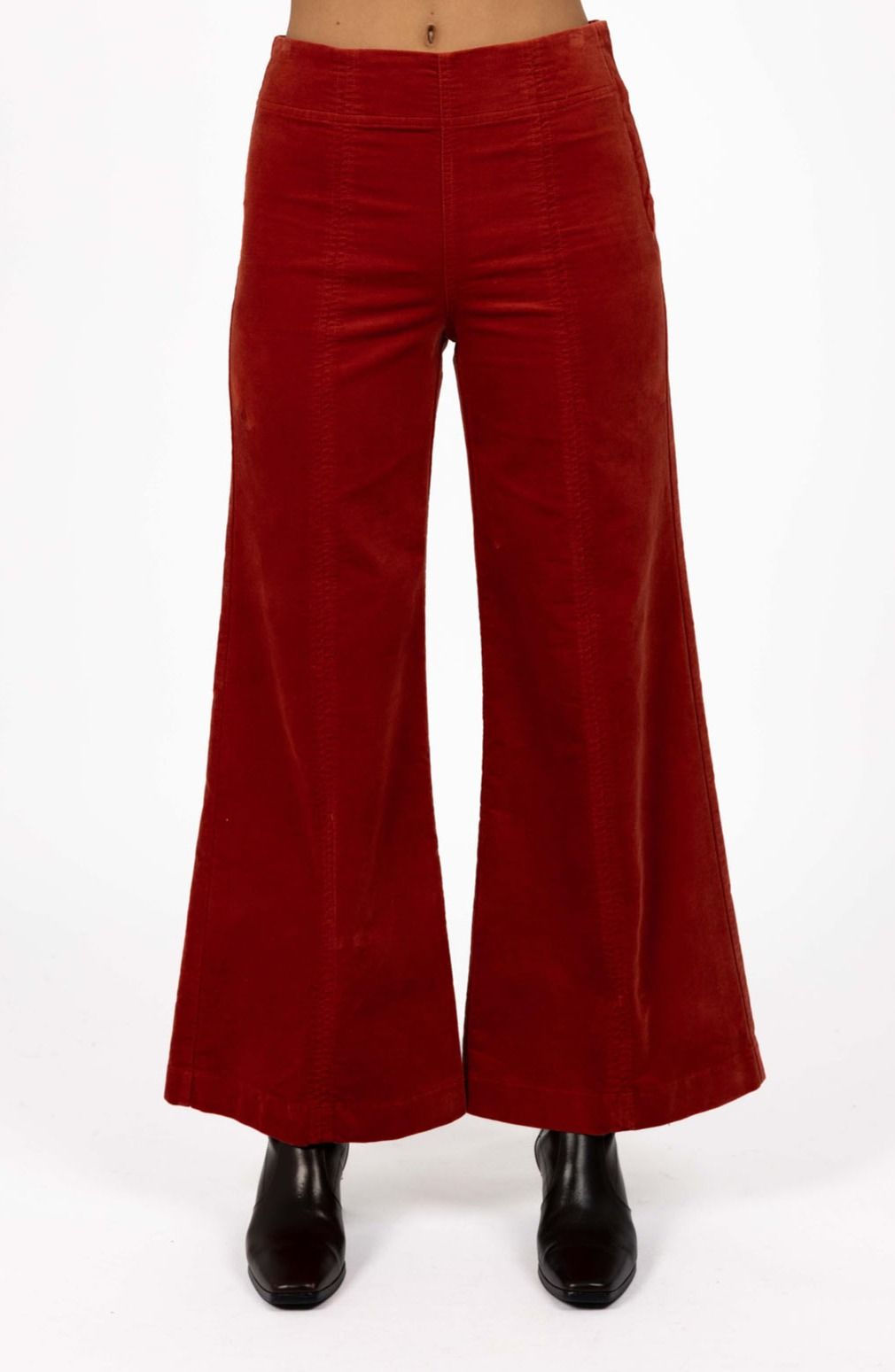 Model in studio wearing Stitched Luxe Pant in Rust with black boots, close-up front view showing stitch lines  