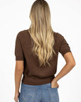 Model in studio wearing Aurora Top in Chocolate with Ryder Jean, close-up back view with one hand in back jean pocket  