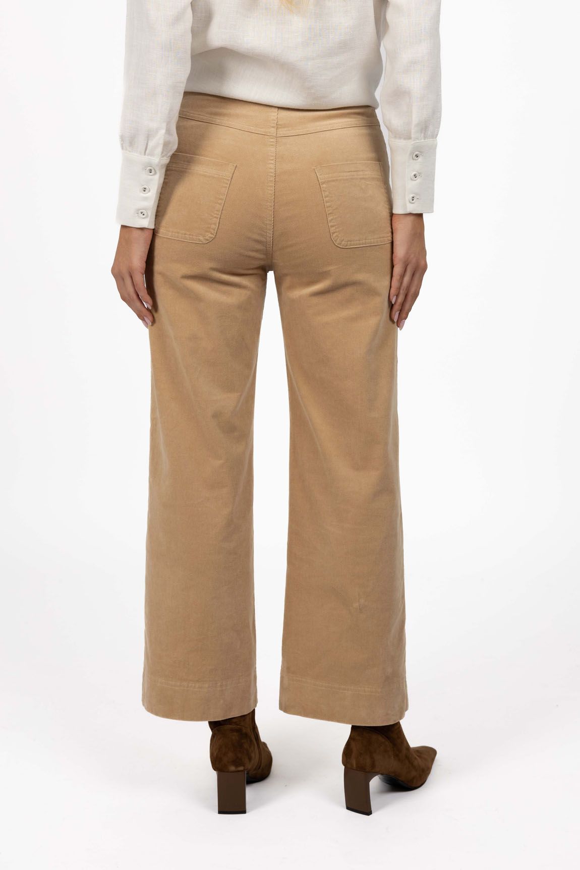 Model in studio wearing Fleetwood Cord Pant in Wheat with Pixie Shirt in White and brown boots, close-up back view 