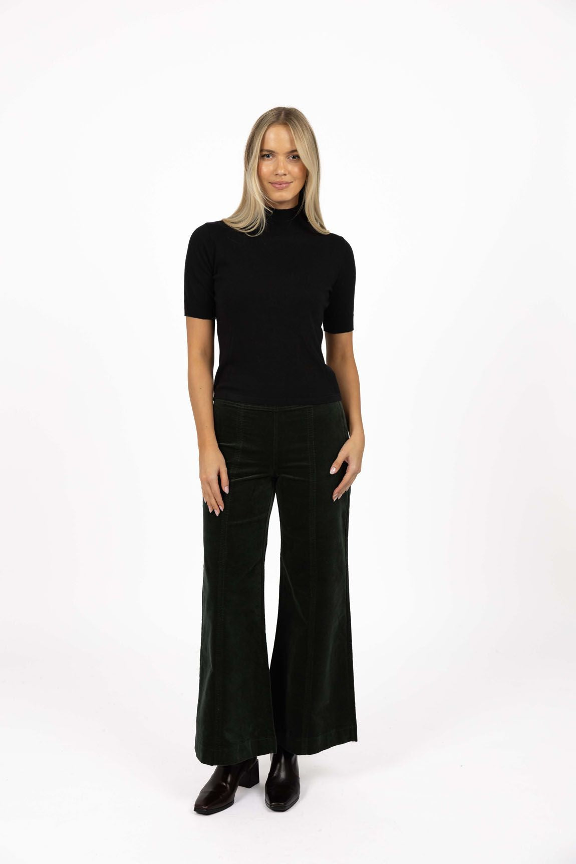 Model in studio wearing Stitched Luxe Pant in Pine with black Vera Top and black boots, full-length front view  