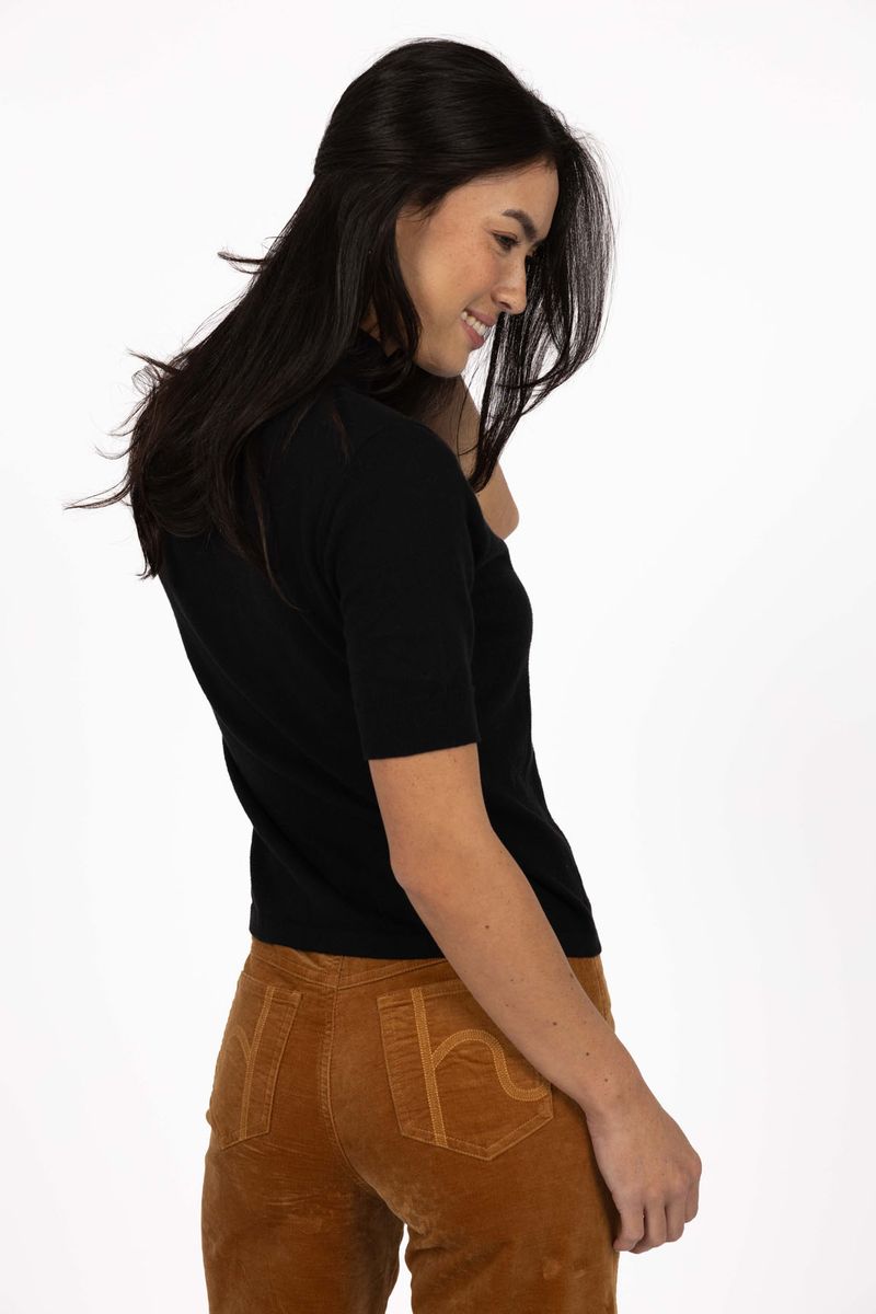 Model in studio wearing Vera Top in Black with Va Va Velour pant in Camel, close up back view looking over shoulder  