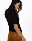 Model in studio wearing Vera Top in Black with Va Va Velour pant in Camel, close up back view looking over shoulder  