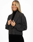 Model in studio wearing Liana Cardi in Charcoal over black skivvy, close-up front-side view holding lapels 