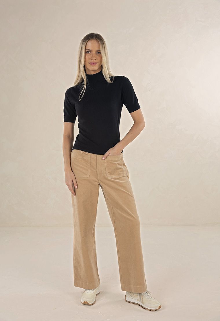 Model in studio wearing Suki Cord Pant in Wheat and Vera Top in Black with cream sneakers, full-length front view  