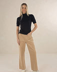 Model in studio wearing Suki Cord Pant in Wheat and Vera Top in Black with cream sneakers, full-length front view  