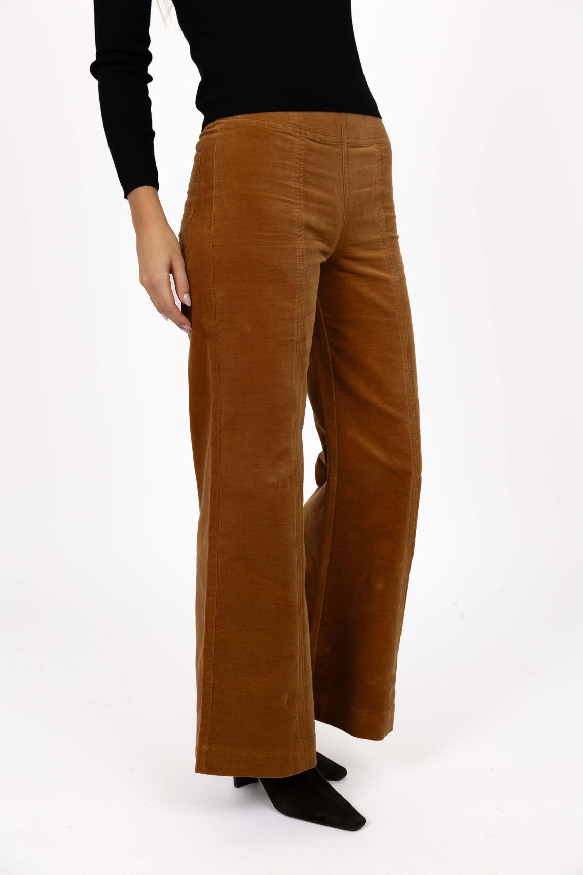 Model in studio wearing Stitched Luxe Pant in Camel with Tempo Top in Black and black boots, close-up front view showing stitch lines  