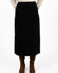 Model in studio wearing Va Va Velour Skirt in Black with brown boots, close-up front view showing midi length 