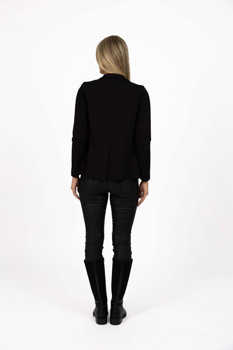 Model in studio wearing Roca Jacket in Black with Status Pants and Stilt Boots, full-length back view 