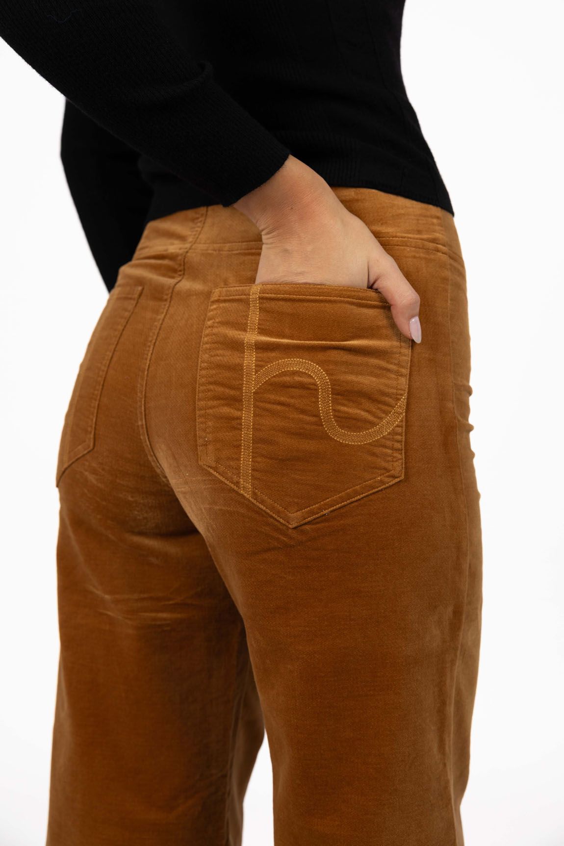 Model in studio wearing Stitched Luxe Pant in Camel with Tempo Top in Black, close-up back view showing pocket embroidery  