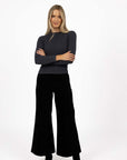 Model in studio wearing Stitched Luxe Pant in Black with Tempo Top in Charcoal with black boots, full-length front view  