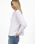 Model in studio wearing Divine Jumper in White with Ryder Jean, close-up side view 
