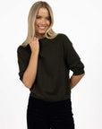 Model in studio wearing Grace Top in Moss with black Va Va Velour Pant, close-up front view 