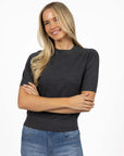 Model in studio wearing Aurora Top in Charcoal with Ryder Jean, close-up front view with arms crossed  