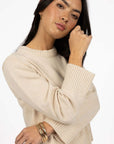 Model in studio wearing Rexie Jumper in Cream with gold bangles, close-up front view showing wide ribbed cuffs 
