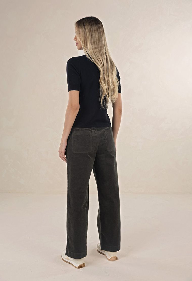 Model in studio wearing Suki Cord Pant in Khaki and Vera Top in Black with cream sneakers, full-length back view 