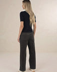 Model in studio wearing Suki Cord Pant in Khaki and Vera Top in Black with cream sneakers, full-length back view 